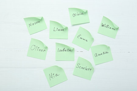 Paper stickers with different names on white wooden background, flat lay. Choosing baby's nameの写真素材