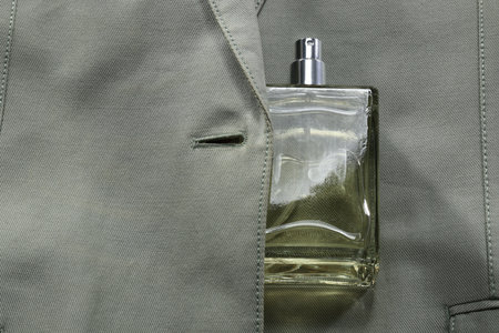 Luxury men's perfume in bottle on gray jacket, top view. Space for text
