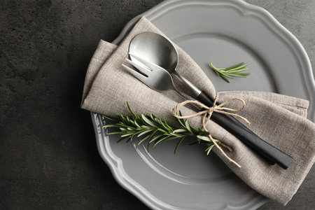 Stylish setting with cutlery and napkin on black table, top view. Space for textの写真素材