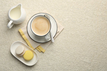 Tasty cappuccino in cup, milk and macarons on light textured table, flat lay. Space for textの写真素材