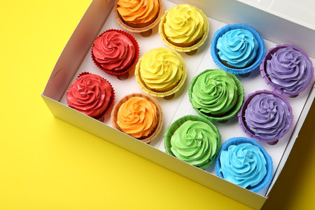 Tasty cupcakes in box on yellow background, above viewの写真素材