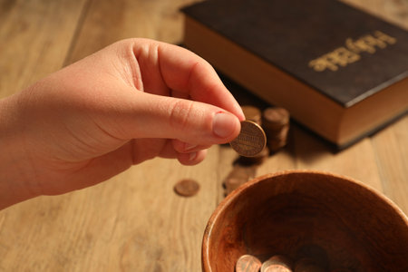 Donate and give concept. Woman putting coin into bowl at table, closeupの写真素材
