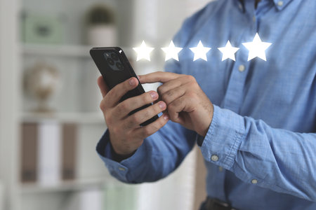 Man leaving service feedback with smartphone at home, closeup. Stars over device