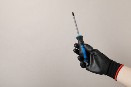 Woman holding screwdriver on gray background, closeup. Space for textの写真素材