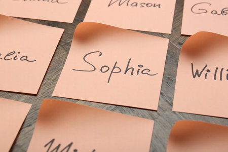 Paper stickers with different names on wooden table, closeup. Choosing baby's nameの写真素材