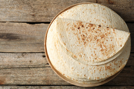 Stack of tasty homemade tortillas on wooden table, top view. Space for textの写真素材