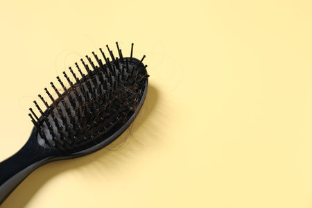 Brush with lost hair on yellow background, space for text