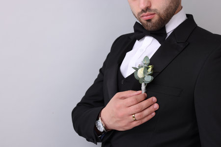 Groom with boutonniere on light grey background, closeup and space for text. Wedding accessory