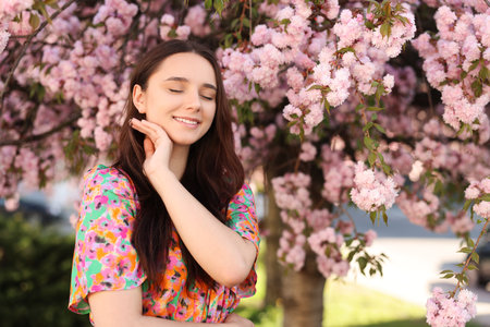 Beautiful woman near blossoming tree on spring dayの写真素材