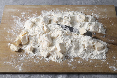 Making short crust pastry. Flour, butter, knife and wooden board on gray tableの写真素材