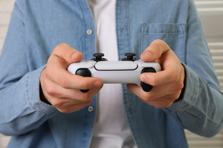 Man using wireless game controller indoors, closeup