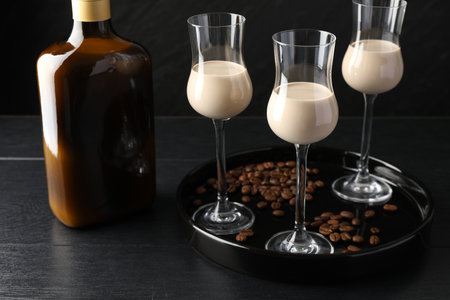 Coffee cream liqueur in glasses, bottle and beans on black wooden tableの写真素材
