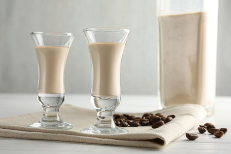 Coffee cream liqueur in glasses and beans on white wooden tableの写真素材