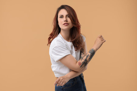 Portrait of beautiful tattooed woman on beige backgroundの写真素材
