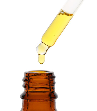 Dripping tincture from pipette into bottle isolated on whiteの写真素材