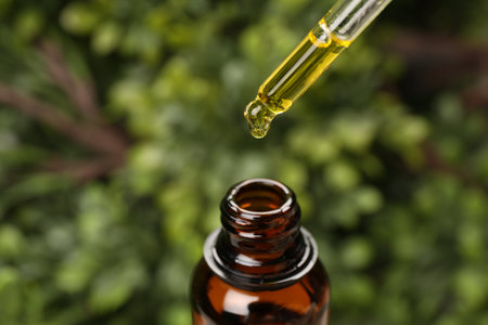 Dripping essential oil from pipette into bottle outdoors, closeupの写真素材