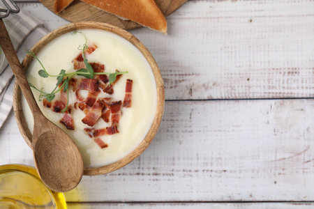 Delicious potato soup with bacon and microgreens in bowl served on wooden table, flat lay. Space for textの写真素材