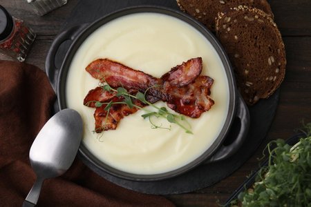 Delicious potato soup with bacon and microgreens in bowl served on wooden table, flat layの写真素材