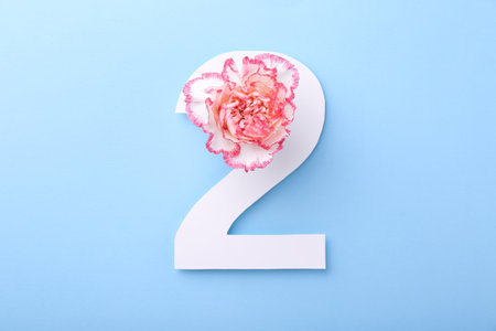 Paper number 2 and beautiful flower on light blue background, top viewの写真素材