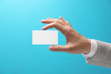 Man with blank business card on light blue background, closeup. Mockup for designの写真素材