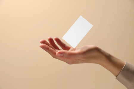 Woman with blank business card on beige background, closeup. Mockup for designの写真素材