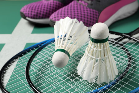 Feather badminton shuttlecocks, rackets and sneakers on court, closeupの写真素材