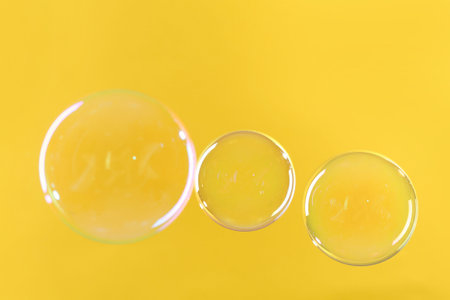 Beautiful transparent soap bubbles on yellow backgroundの写真素材