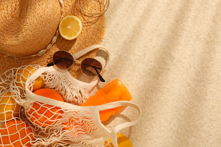 String bag with sunglasses, straw hat and fruits on beige textured background, flat lay. Space for textの写真素材