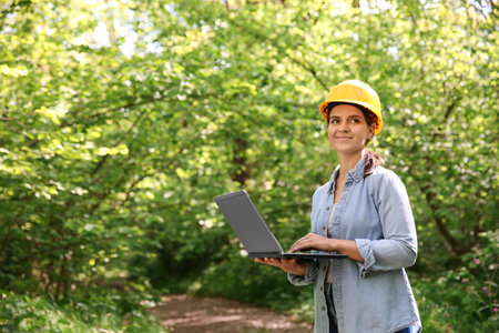Forester with laptop examining plants in forest, space for textの写真素材