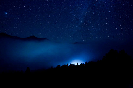 Sky with twinkling stars over mountains at nightの写真素材