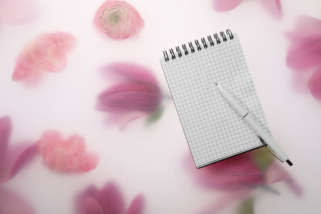 Guest list. Notebook and pen on spring floral background, flat lay. Space for textの写真素材