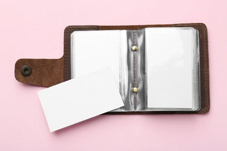Leather business card holder with blank cards on pink background, top view