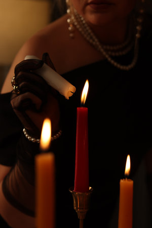 Woman with elegant jewelry lightning up candle indoors, closeupの写真素材