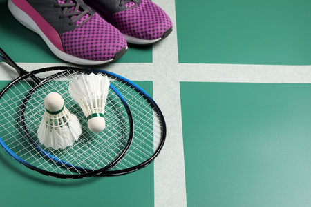 Feather badminton shuttlecocks, rackets and sneakers on court, space for textの写真素材