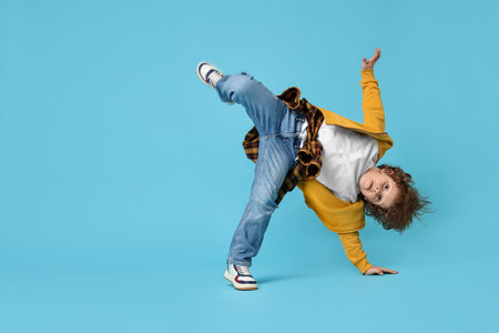 Happy little boy dancing on light blue backgroundの写真素材