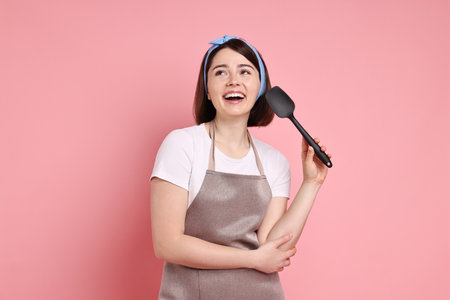 Happy confectioner with spatula on pink backgroundの写真素材