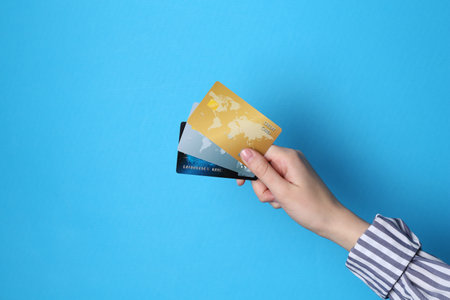 Woman holding credit cards on light blue background, closeupの写真素材