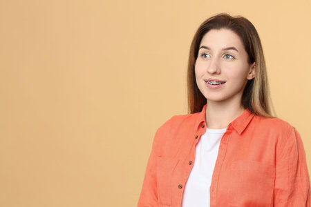 Portrait of smiling woman with dental braces on beige background. Space for textの写真素材