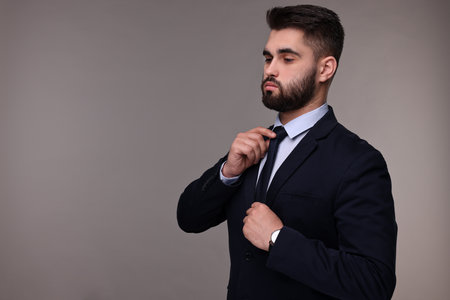 Handsome businessman in suit and necktie on grey background. Space for textの写真素材