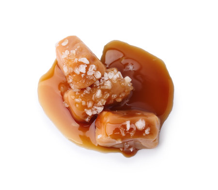 Yummy caramel candies and sea salt isolated on white, top viewの写真素材