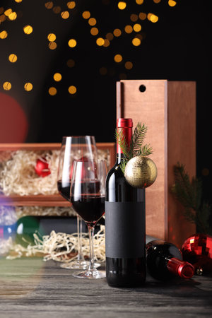 Bottles of wine, glasses, wooden boxes, fir twigs and Christmas balls on tableの写真素材