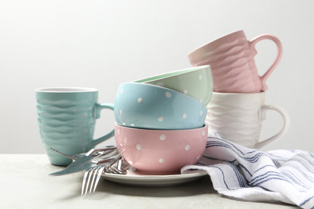 Beautiful ceramic dishware, cups and cutlery on light gray table