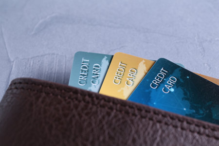 Credit cards in leather wallet on gray textured table, closeup