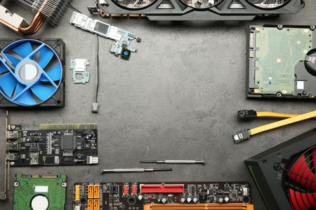 Frame of graphics card and other computer hardware on gray textured table, flat lay. Space for text