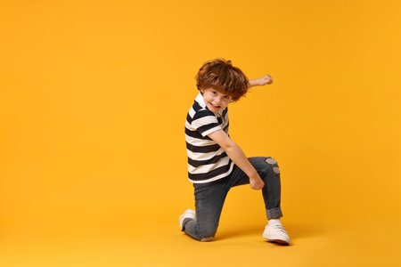 Happy little boy dancing on yellow background. Space for textの写真素材