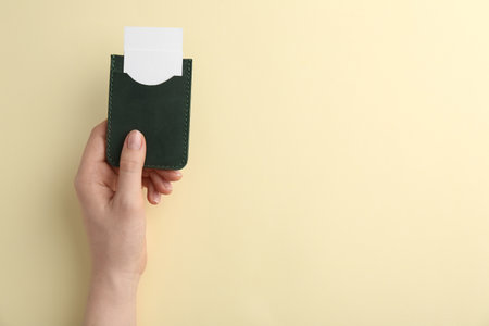 Woman holding business card holder with blank cards on light yellow background, top view. Space for textの写真素材