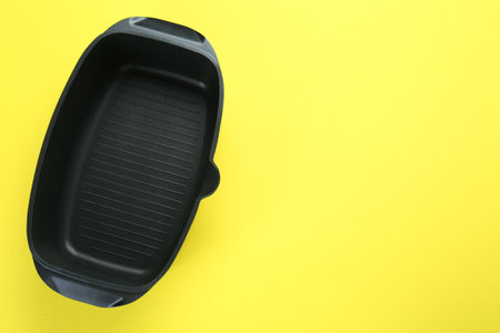 Black pot on yellow background, top view. Space for textの写真素材