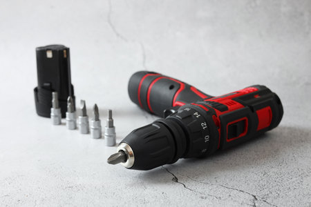 Electric screwdriver, drill bits and battery on light table