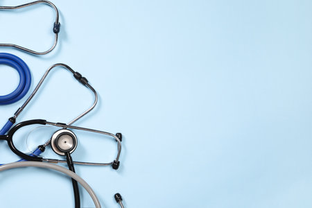 Stethoscopes on light blue background, flat lay. Space for textの写真素材