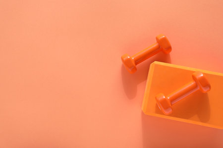 Dumbbells and yoga block on coral background, flat lay. Space for textの写真素材
